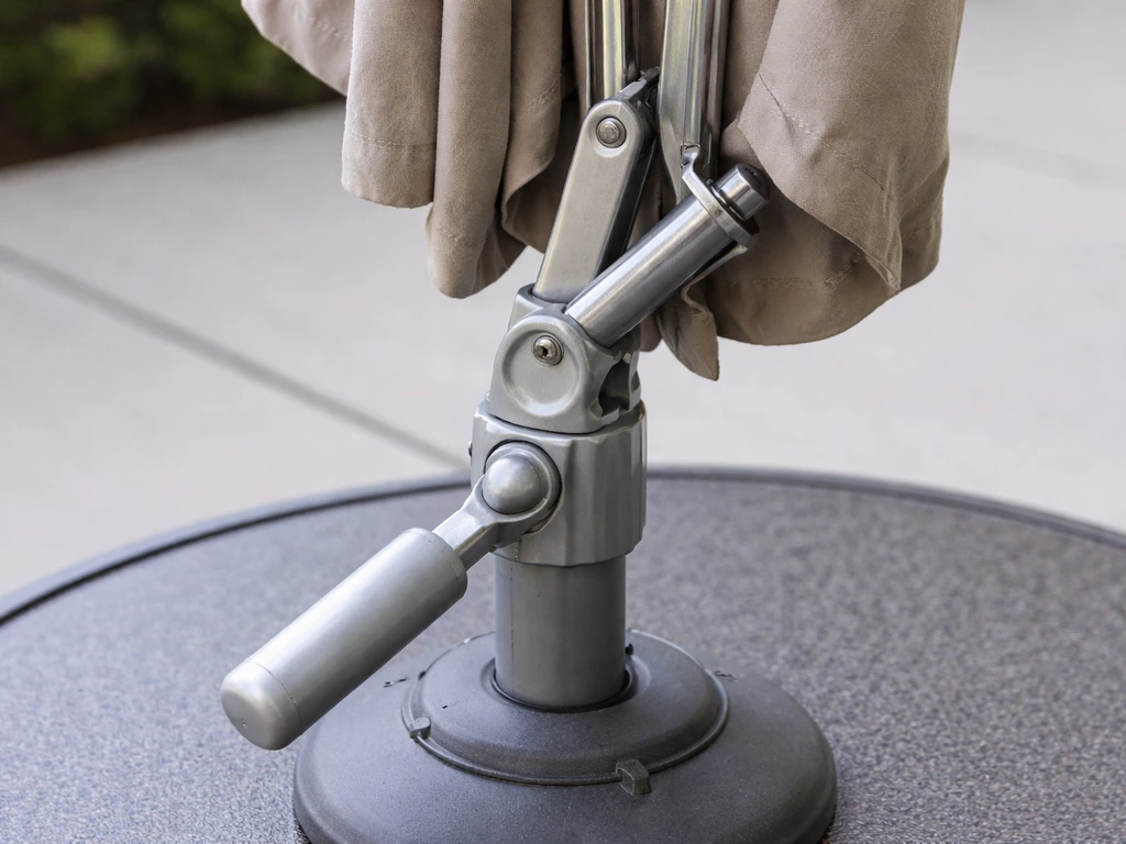 Closed patio umbrella showing the tilt housing pinch points and a bent arm segment near the pivot.