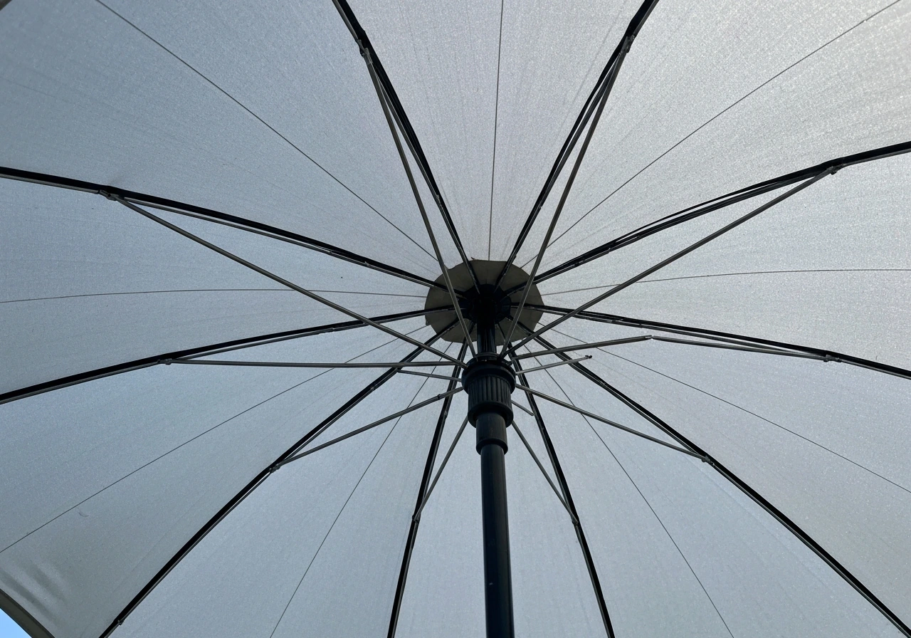 Camera looks up inside an open umbrella canopy to inspect the central hub and rib sockets.
